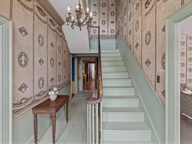 stairway featuring ornamental molding and a notable chandelier