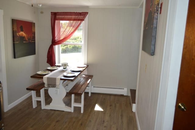 dining room with a baseboard heating unit, wood finished floors, ornamental molding, and baseboards