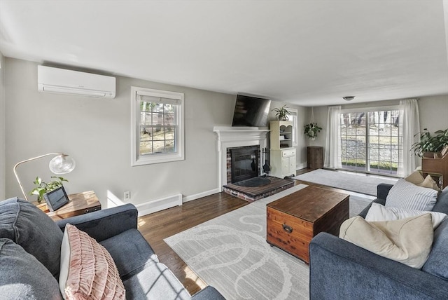 living area with a glass covered fireplace, plenty of natural light, a wall unit AC, and wood finished floors