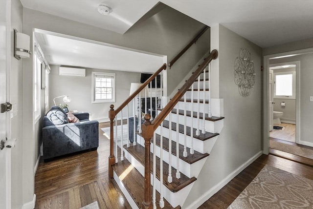 stairs featuring baseboards, a wall mounted AC, and wood finished floors