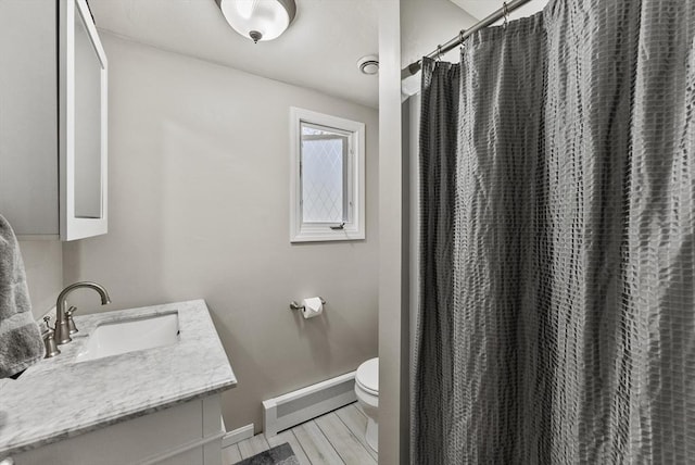 full bathroom with baseboard heating, wood finished floors, vanity, baseboards, and toilet