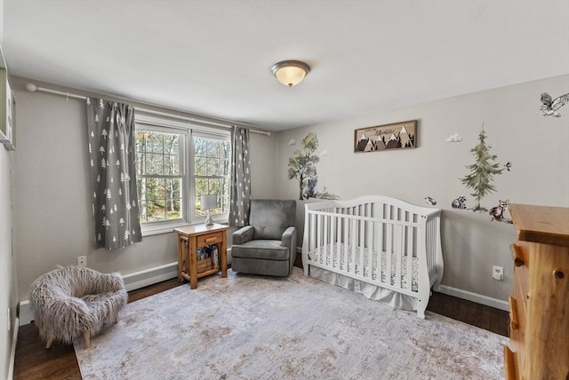 bedroom with baseboards, a nursery area, and wood finished floors