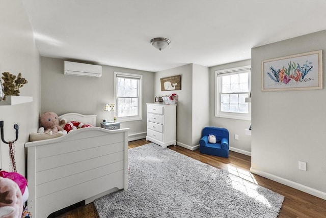 bedroom featuring wood finished floors, baseboards, and a wall mounted AC