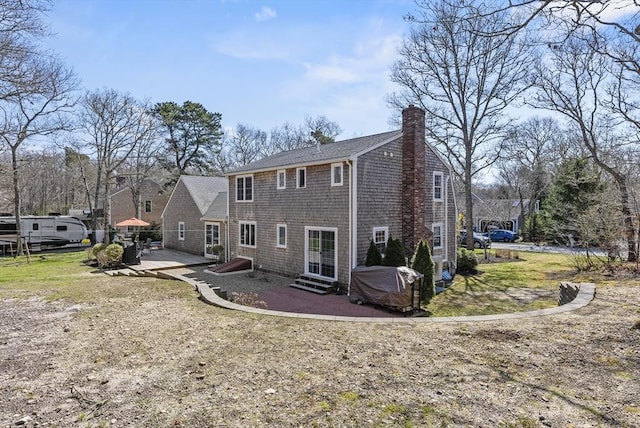rear view of house with a patio, a lawn, a chimney, and entry steps