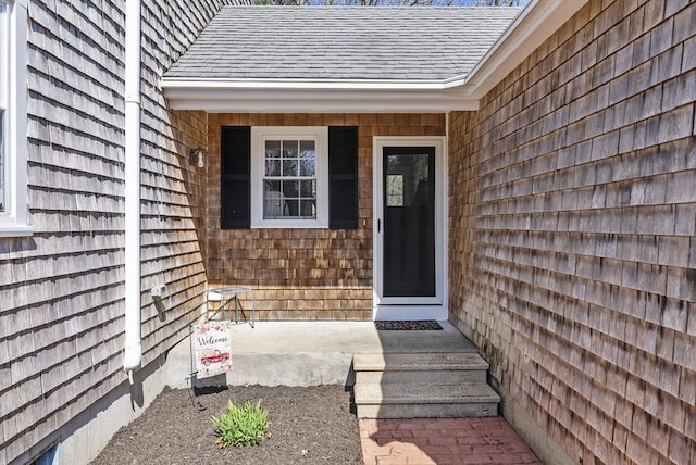 view of exterior entry with a shingled roof