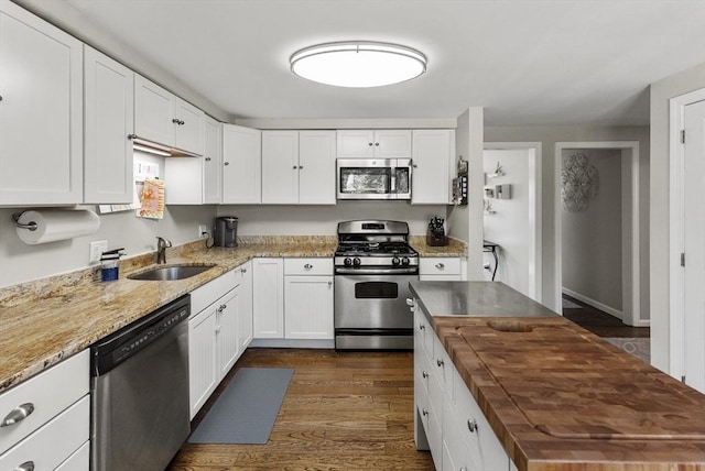 kitchen featuring a sink, wood counters, white cabinets, and stainless steel appliances