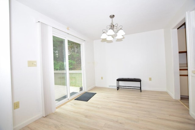 unfurnished dining area featuring a chandelier, light wood-style flooring, and baseboards
