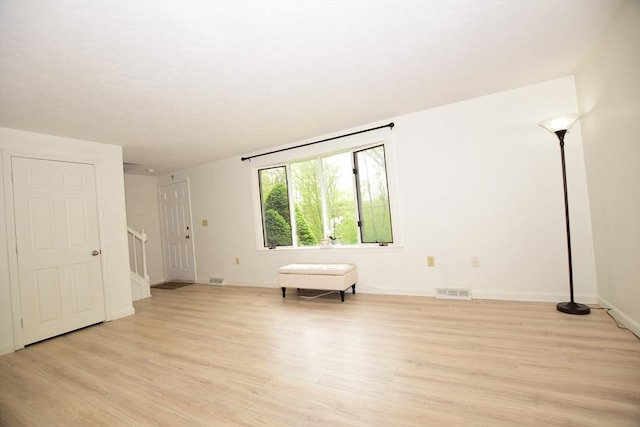 unfurnished room featuring light wood-type flooring, stairway, and baseboards