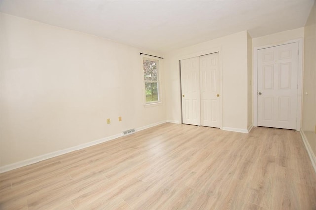 unfurnished bedroom with light wood-style floors, baseboards, and a closet
