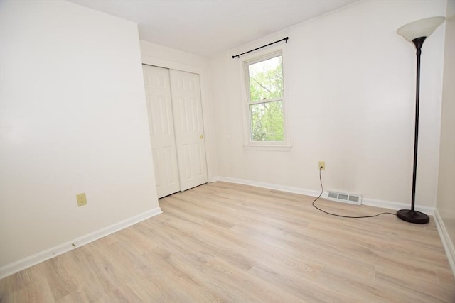 unfurnished bedroom featuring light wood finished floors, baseboards, and a closet