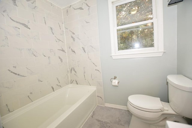 bathroom featuring toilet, baseboards, and shower / washtub combination