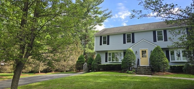 colonial-style house featuring a front lawn and entry steps