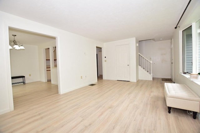 living area with stairs, light wood finished floors, a chandelier, and baseboards
