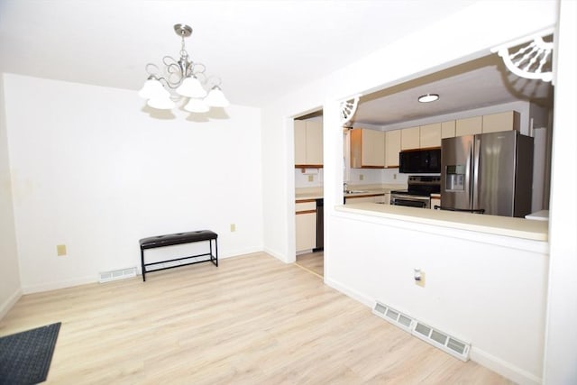 kitchen with appliances with stainless steel finishes, a chandelier, light wood-style flooring, and light countertops