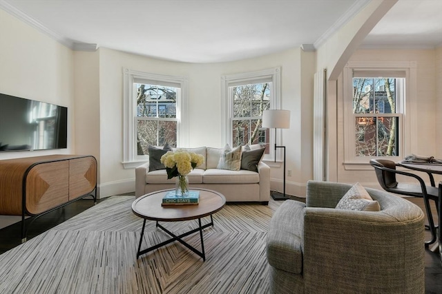 living room featuring crown molding, arched walkways, baseboards, and wood finished floors