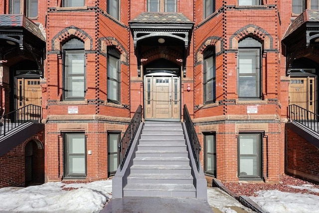 snow covered property entrance with brick siding