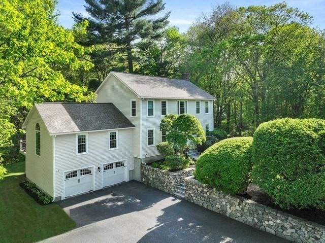 view of front facade featuring driveway, an attached garage, and view of wooded area