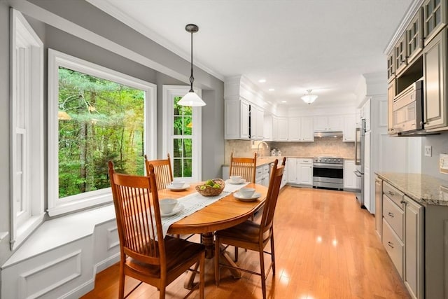 dining space featuring healthy amount of natural light, light wood-type flooring, crown molding, and recessed lighting