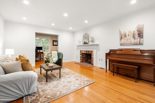 living room with light wood-style flooring, recessed lighting, a brick fireplace, and baseboards
