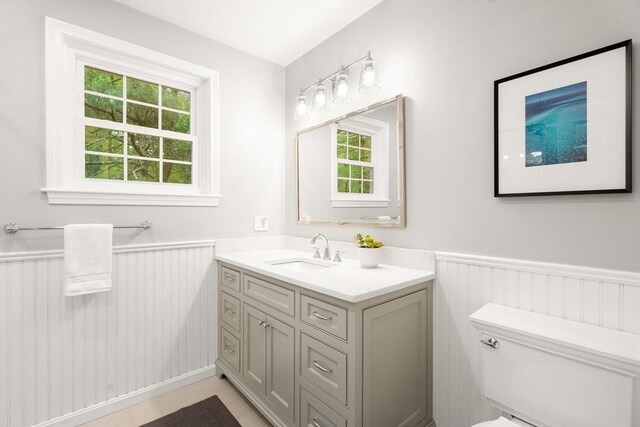 bathroom featuring wainscoting, healthy amount of natural light, vanity, and toilet