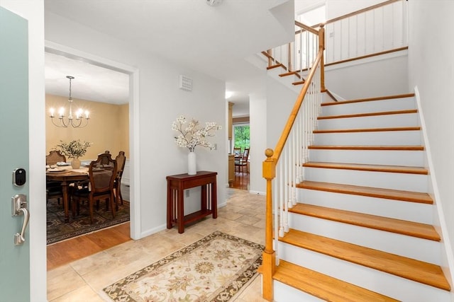 stairs featuring a chandelier and baseboards