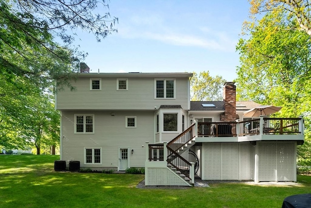 back of house featuring a chimney, stairs, a deck, a yard, and central AC unit