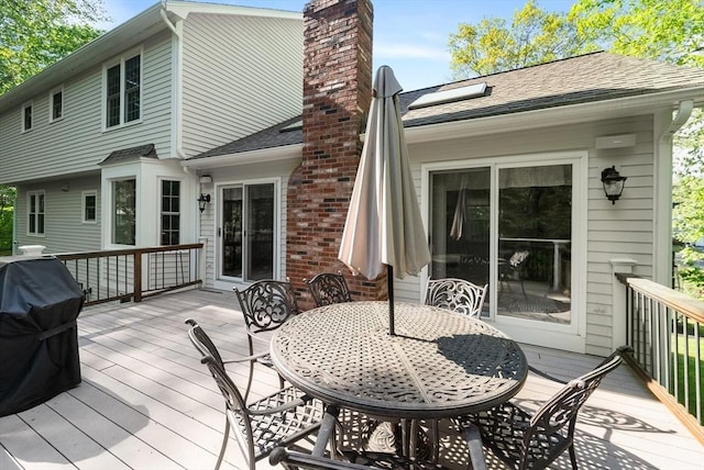 wooden terrace featuring a grill and outdoor dining space