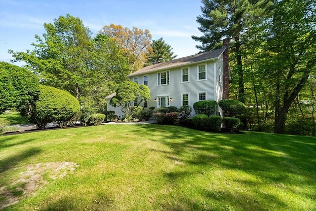 view of front of home featuring a chimney and a front lawn