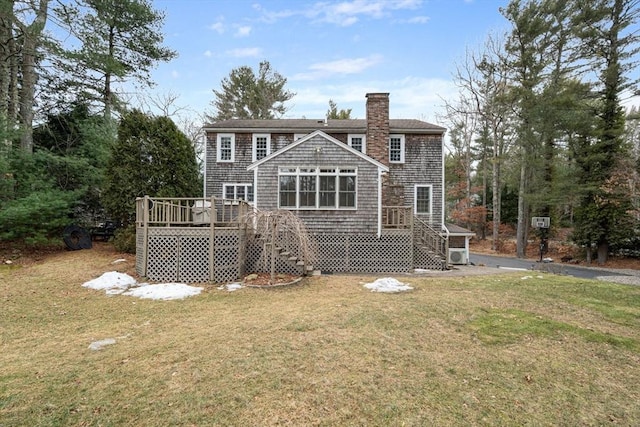 rear view of property featuring a chimney, a deck, and a yard