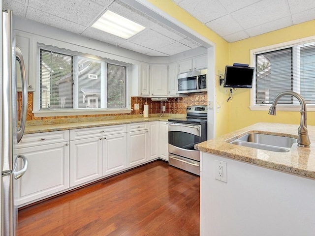 110 Reed St, Cambridge, MA 02140 - kitchen featuring appliances with stainless steel finishes, a sink, a paneled ceiling, white cabinets, and dark wood-style flooring