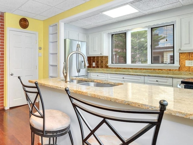 110 Reed St, Cambridge, MA 02140 - kitchen with a paneled ceiling, stainless steel fridge with ice dispenser, white cabinetry, light stone countertops, and tasteful backsplash