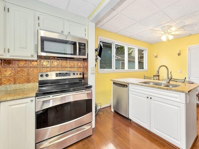 110 Reed St, Cambridge, MA 02140 - kitchen with appliances with stainless steel finishes, a sink, white cabinetry, wood finished floors, and tasteful backsplash