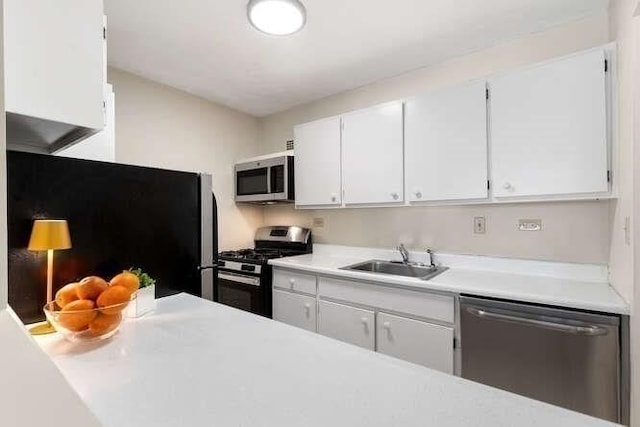 kitchen featuring stainless steel appliances, a sink, light countertops, and white cabinetry