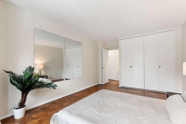 bedroom featuring baseboards and two closets