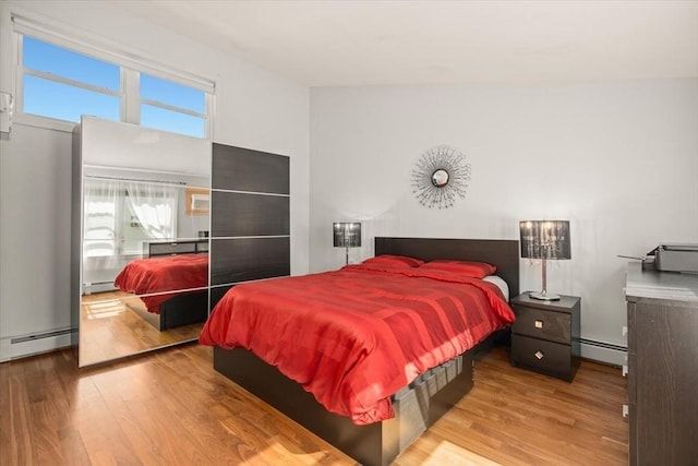 bedroom featuring baseboard heating, a baseboard heating unit, and wood finished floors