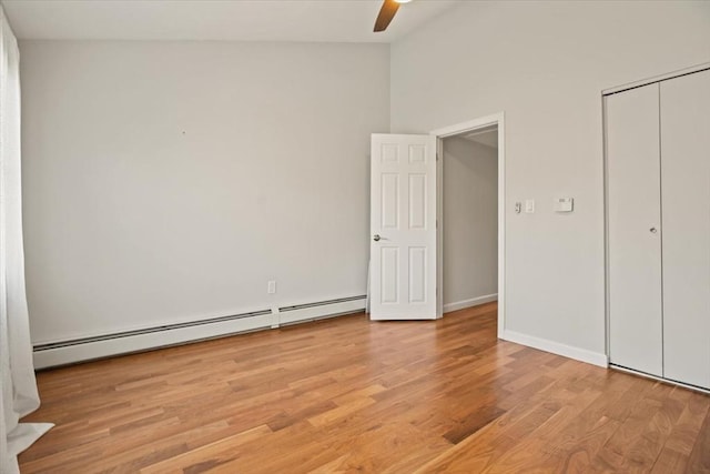 unfurnished bedroom with ceiling fan, light wood-style floors, baseboards, a baseboard heating unit, and a closet