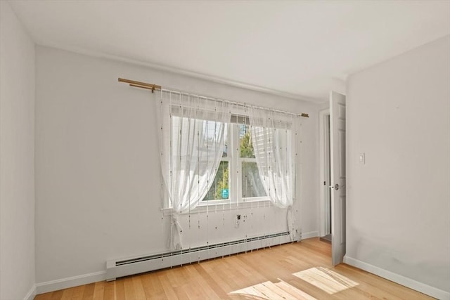 unfurnished room with baseboards, a baseboard radiator, and wood finished floors