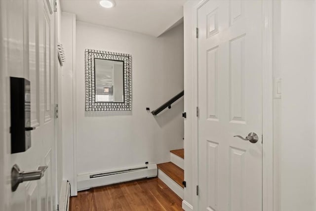 stairway featuring baseboard heating and wood finished floors
