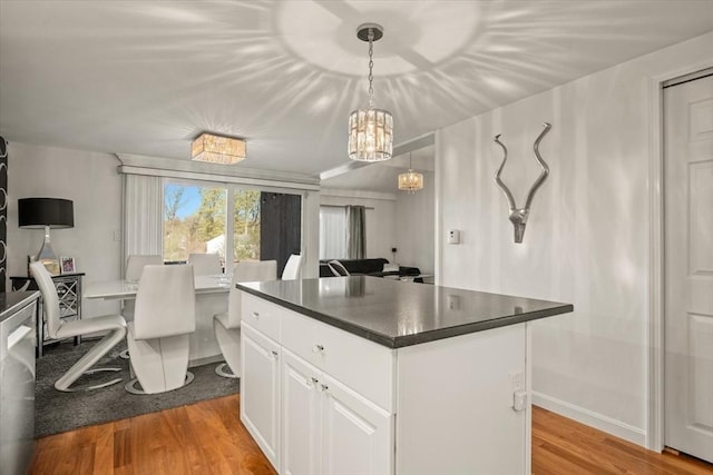 kitchen featuring white cabinets, dark countertops, a chandelier, light wood-type flooring, and a kitchen island