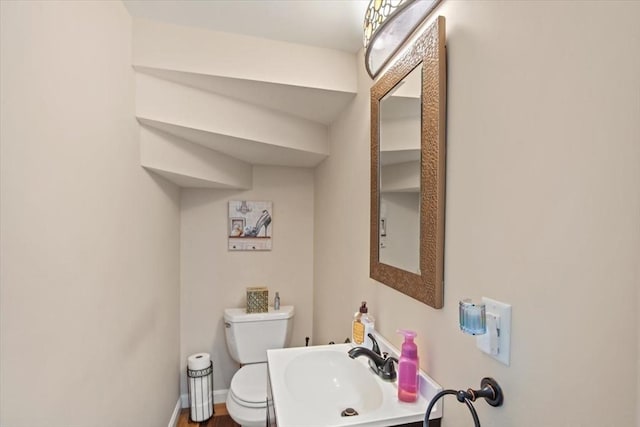 bathroom featuring a sink, baseboards, and toilet