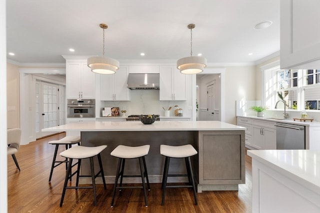 kitchen featuring white cabinetry, wall chimney range hood, appliances with stainless steel finishes, and dark hardwood / wood-style floors