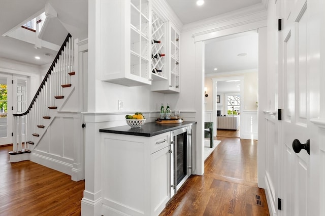 bar featuring white cabinets, beverage cooler, dark hardwood / wood-style flooring, and crown molding