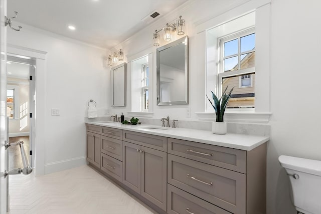 bathroom with toilet, vanity, parquet flooring, and crown molding