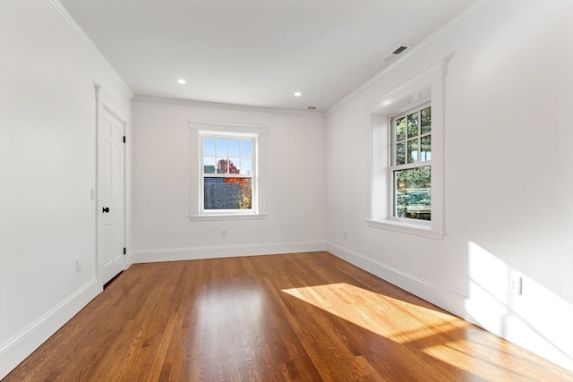 spare room with wood-type flooring, a healthy amount of sunlight, and crown molding