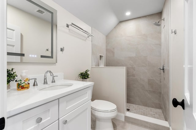 bathroom with tile patterned floors, a tile shower, vanity, toilet, and lofted ceiling