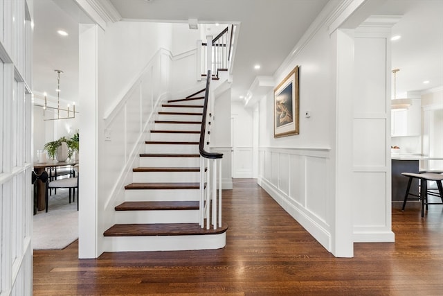 staircase featuring a notable chandelier, hardwood / wood-style flooring, and crown molding