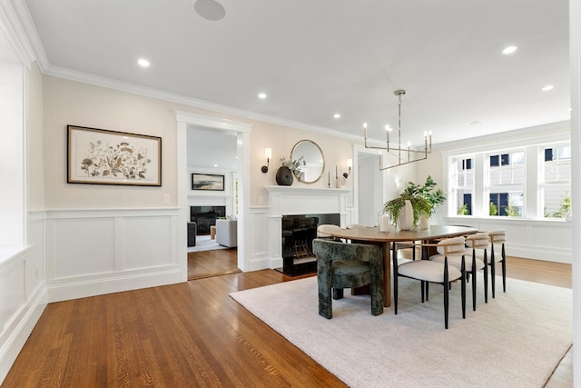 dining space with ornamental molding, light wood-type flooring, and an inviting chandelier