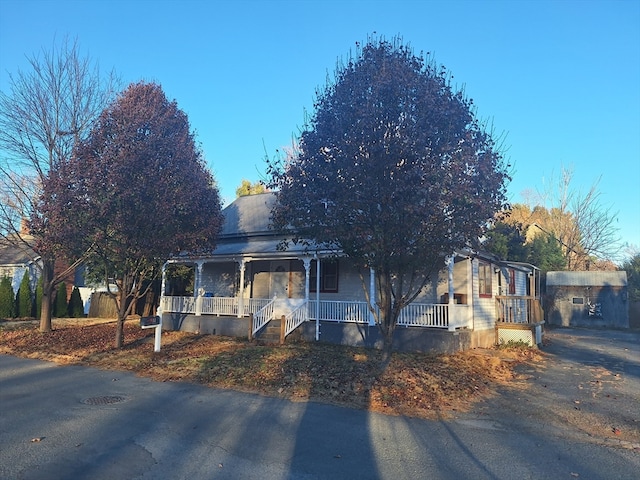 view of front of home featuring a porch and a storage shed