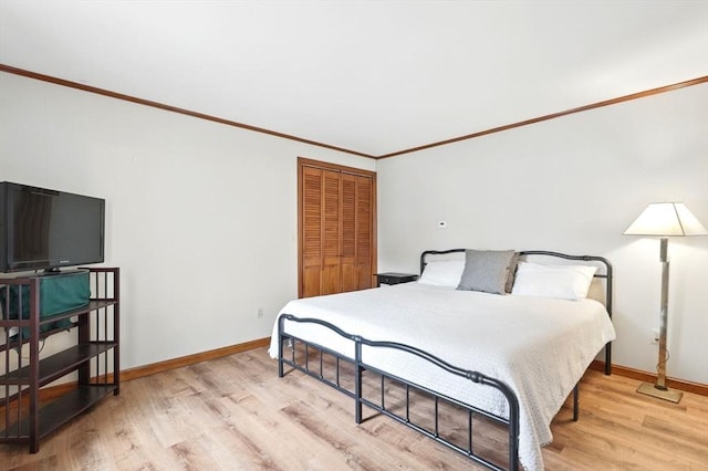 bedroom with baseboards, ornamental molding, a closet, and light wood-style flooring
