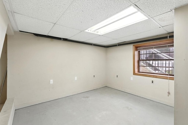 basement featuring baseboards and a drop ceiling